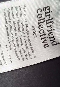 Ruhacímke, amelyen a "girlfriend collective" felirat szerepel, #1002 cikkszámmal és gyártási adatokkal több nyelven.