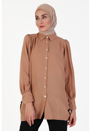 Langärmliges Hemd in warmem Beige mit Kragen, Puffärmeln und Holzknöpfen auf der Vorderseite. Glatter Stoff mit Seitenschlitzen.