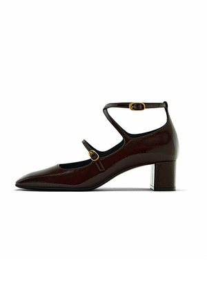 Chaussure en cuir verni bordeaux foncé avec un bout pointu, une bride à la cheville, une boucle en métal doré et un petit talon carré. Texture lisse, design élégant.