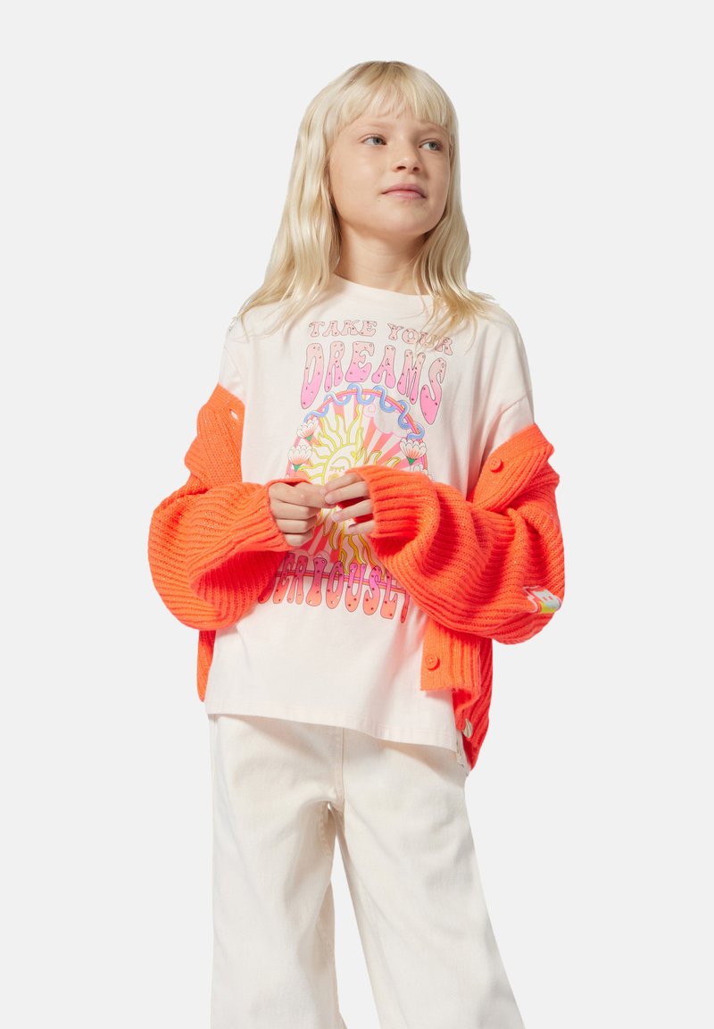 Neon oranje gebreide cardigan met knoopdetails, gedragen over een lichtgekleurde T-shirt met korte mouwen, voorzien van kleurrijke grafische tekst en een zonontwerp.