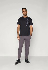 Čierne tričko s krátkym rukávom s logom a textovým detailom; šedé tepláky s elastickými manžetami; čierne športové topánky.