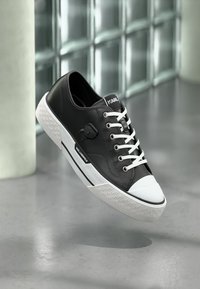 Μαύρα δερμάτινα αθλητικά παπούτσια με λευκό κάλυμμα δαχτύλων και σόλα. Διαθέτουν λευκά κορδόνια και λεπτομέρεια λογότυπου στο πλάι. Υφή στη σόλα με γεωμετρικό μοτίβο.