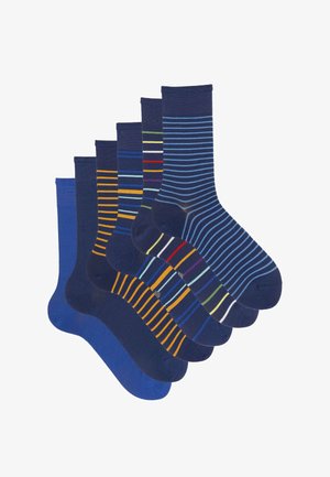 Zes paar heren crew sokken in verschillende blauwtinten, sommige met meerkleurige horizontale strepen, overlappend gerangschikt op een witte achtergrond.