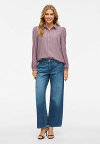 Lys lavendel knap-op skjorte med strukturerte striper og puff-ermer, kombinert med høy midje, vide blå jeans og svarte stroppede hæler.