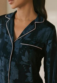 Navy floral-patterned pajama top with light pink piping, featuring a chest pocket and a soft, satin-like texture.