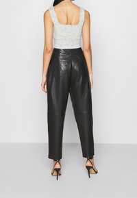 Szary prążkowany top na ramiączkach z kwadratowym dekoltem z tyłu, zestawiony z wysokim stanem czarnych spodni z eko-skóry, które mają dwie tylne kieszenie i smukłe, zwężane nogawki.