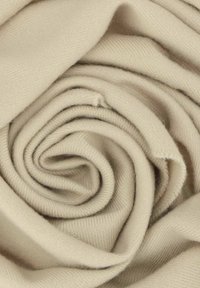 Tissu tricoté beige disposé en spirale, mettant en avant une texture lisse avec un tissage fin et un éclat subtil. Aucune motif ou matériel visible.