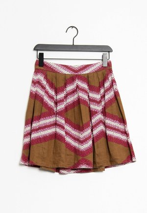 Falda plisada marrón con un patrón en zigzag rosa y blanco, con una cintura plana y colgada de una percha negra. Tela de algodón.