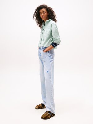 Groen en wit gestreepte cropped shirt, lichtblauwe verzeilde denimjeans en zwarte slippers met luipaardprintaccenten.