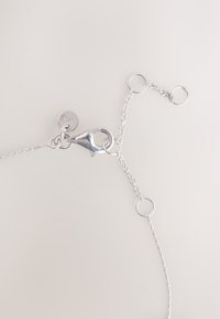 Silver chain with a clasp and multiple rings. Features a round tag with "925" marking. Thin links with a polished finish.