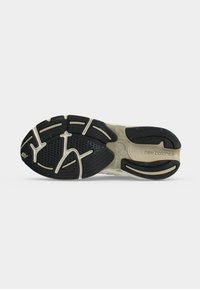 Σόλα από αθλητικό παπούτσι New Balance με μαύρο και μπεζ καουτσούκ πέλμα, υφή για καλύτερη πρόσφυση και σήμανση "new balance" στην περιοχή του μέσου ποδιού.