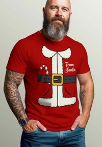 Red cotton t-shirt featuring a Santa costume graphic, white faux fur trim, candy cane, and "Team Santa" text in a playful font.