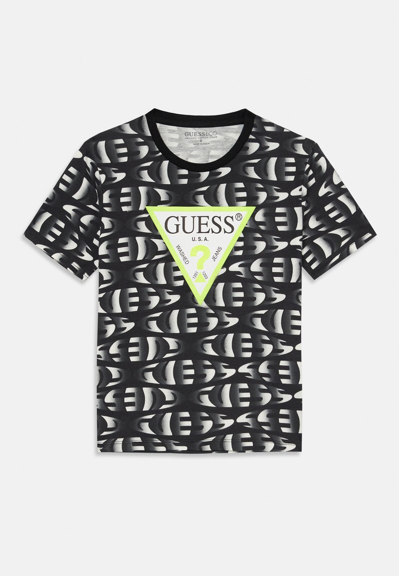 T-shirt noir en coton avec un motif répété et un grand triangle vert portant le logo "GUESS" en blanc, manches courtes, encolure ronde.
