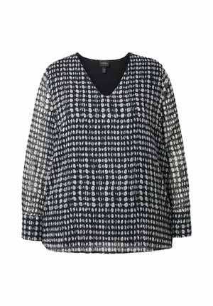 Blusa de manga larga en negro y blanco con escote en V, tejido texturizado y un patrón de pequeñas formas ovaladas dispuestas en una cuadrícula.