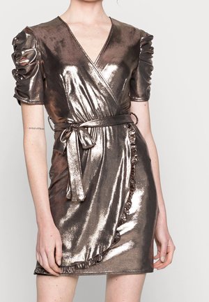 Woman wearing a metallic bronze wrap dress with ruched short sleeves, a tied waist belt, and ruffled trim on the wrap skirt.