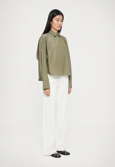Olive green, striped, cropped button-up shirt with long sleeves, paired with white wide-leg pants and black slip-on shoes.