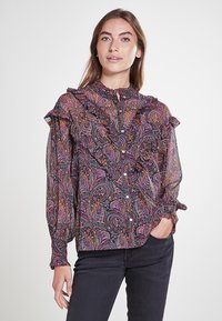 Blusa negra transparente con un colorido patrón de paisley, cuello fruncido, mangas largas y cierre de botones. Tela texturizada con diseños intrincados.