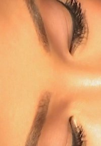 Close-up of closed eyes with defined dark eyelashes, smooth skin texture, subtle eyeshadow, and a natural brow shape.