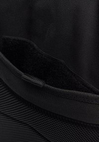 Svart tygpung med en slät yta och nätstruktur, kardborrestängning och ett mjukt innerfoder, utformad för säker förvaring.