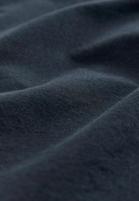 Tejido azul oscuro con una textura suave, que muestra sutiles arrugas y pliegues, destacando su calidad ligera y transpirable.