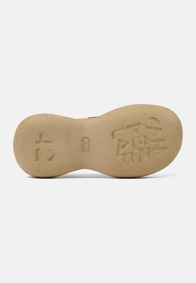 Suela de zapato de goma en color beige claro, con una superficie texturizada que presenta un patrón de formas geométricas y detalles de marca impresos.