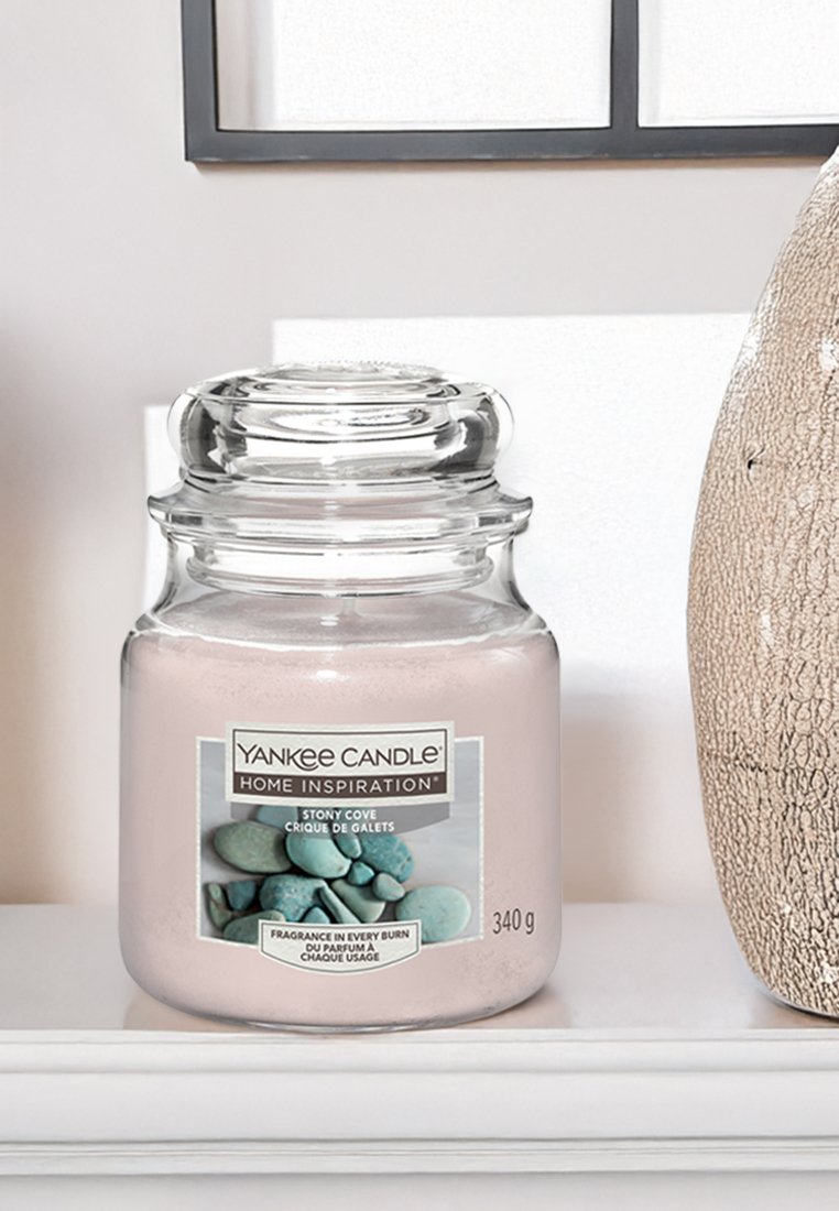 Yankee Candle in un barattolo di vetro trasparente, con un interno di cera rosa e un'etichetta con pietre blu. Coperchio robusto e base rotonda. 340 g.