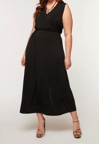 Svart, ärmlös maxi-klänning med inslagsdesign och elastisk midja. Kombinerad med flerfärgade platåskor med ormskinnsmönster.