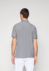 Camisa polo cinza de mangas curtas com colarinho e tecido texturizado. Apresenta uma bainha reta e aberturas laterais para maior conforto.