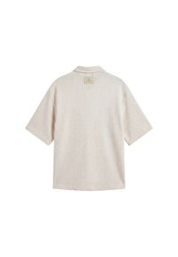 Chemise beige à manches courtes en tricot gaufré avec une petite étiquette carrée au haut du dos, sous le col.