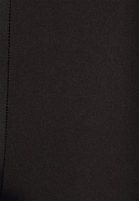 Tecido preto com uma textura suave, apresentando um brilho sutil. Uma costura visível corre ao longo de uma borda. Sem padrões ou acessórios visíveis.