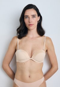 Sutien bege almofadado com alças ajustáveis, textura suave e forma estruturada. Apresenta um fecho em gancho nas costas e um design minimalista.