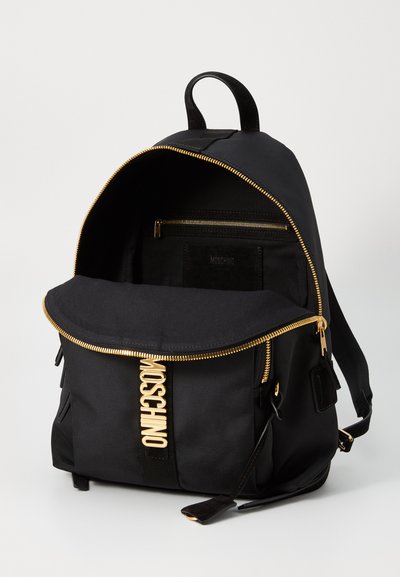 Rucsac negru din țesătură, cu fermoar și accesorii aurii. Are închidere cu clapetă, buzunar frontal și compartiment interior de depozitare.