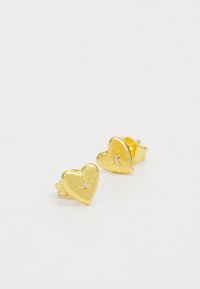 Pendientes de stud en forma de corazón dorados con superficie texturizada y una pequeña gema clara en el centro. Diseño de clip para un uso seguro.