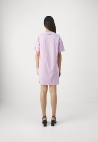 Liliowa sukienka t-shirtowa z krótkimi rękawami, z bocznymi rozcięciami i małym logo nadrukowanym w pobliżu dekoltu. Gładki bawełniany materiał.