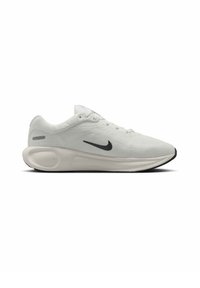 Svetlošedá športová obuv s textúrovaným sieťovým zvrškom, čiernym logom Nike, šnurovacím dizajnom a kontrastnou čiernou gumovou podrážkou.