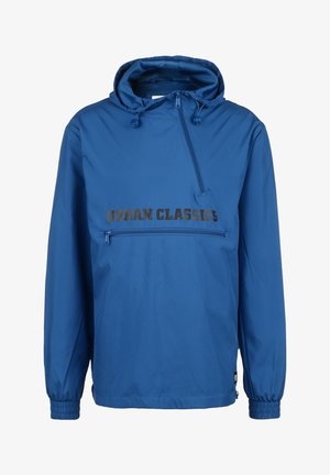 Sinine kapuutsiga jakk, millel on eesnezip-tasku, elastsed varrukad ja "URBAN CLASSICS" musta värviga trükituna rinna kohal. Kerge, sile tekstuur.