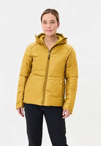 Geel geïsoleerd jack met capuchon, voorzien van een rits aan de voorkant en een doorgestikte structuur. Gedragen met een zwarte broek, tegen een witte achtergrond.