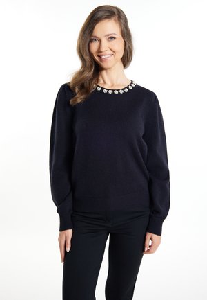 Maglione lavorato a maglia blu navy con scollatura rotonda, decorato con dettagli floreali. Presenta maniche lunghe e polsini e orlo a coste.