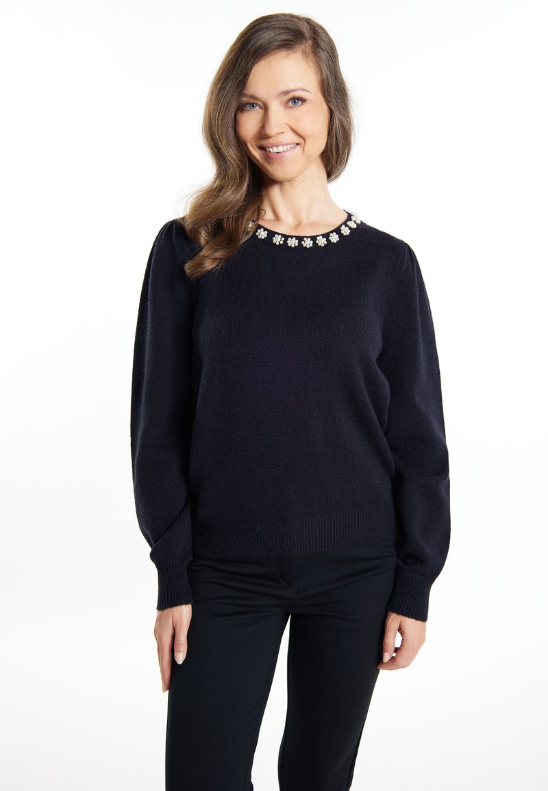 Maglione lavorato a maglia blu navy con scollatura rotonda, decorato con dettagli floreali. Presenta maniche lunghe e polsini e orlo a coste.