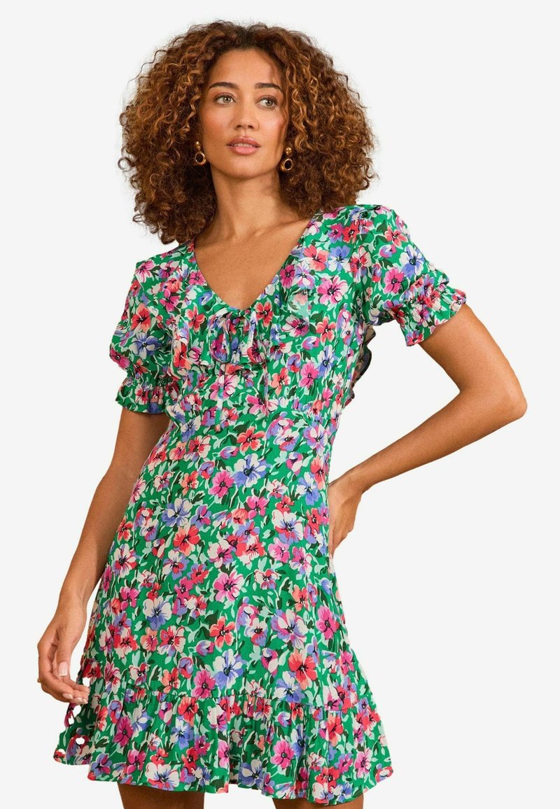 Lillelillelise roheline alus, millel on roosa ja sinine muster, lühikesed puhvis varrukad, V-kaelus ja volangiga ääreosa. Puuvillane materjal.