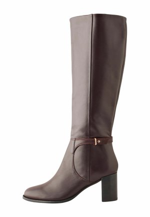 Stivale da donna alto in pelle marrone scuro con tacco a blocco, punta leggermente appuntita e cinturino decorativo con fibbia dorata attorno alla caviglia.