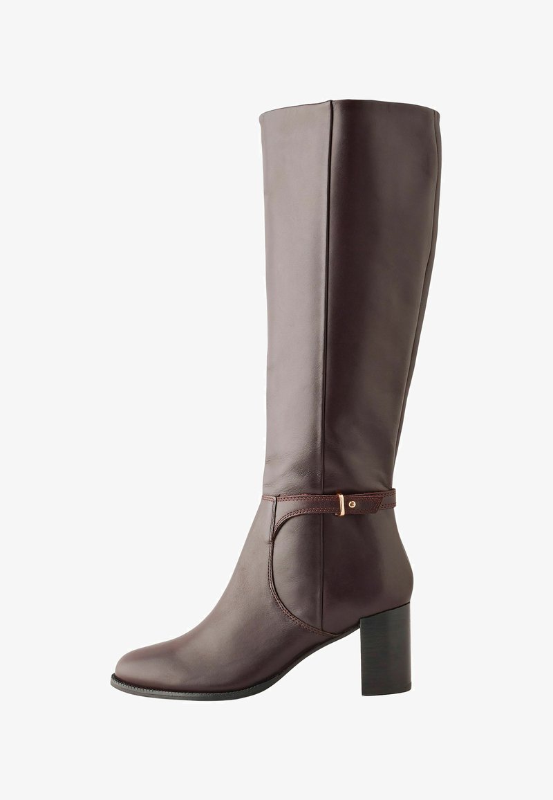 Botín de mujer de cuero marrón oscuro, alto, con tacón cuadrado, punta ligeramente afilada y correa decorativa con hebilla dorada alrededor del tobillo.