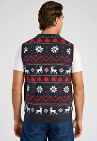 Suéter sin mangas de punto con base azul marino, que presenta renos blancos, copos de nieve, árboles y detalles rojos en un patrón geométrico festivo.