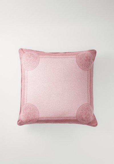 Square pink pillow with a textured finish, featuring a decorative border and circular accents in each corner. Soft fabric with subtle patterns.