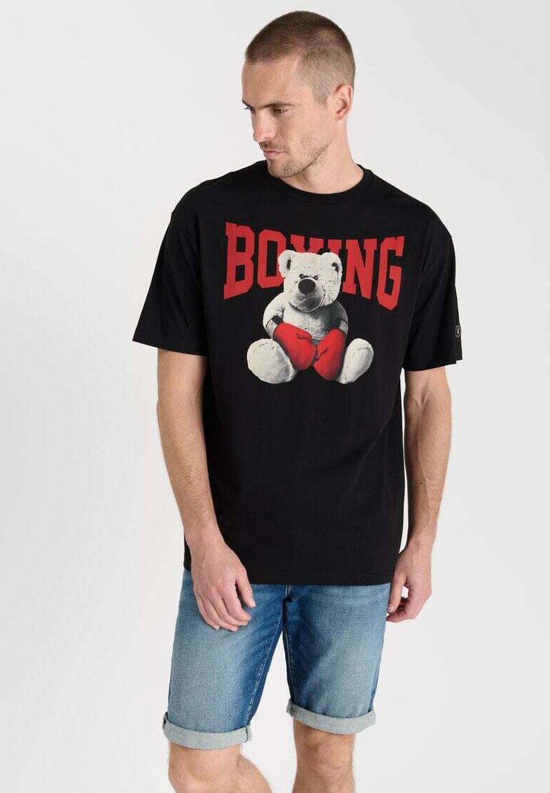 Camiseta negra con un gráfico impreso de un oso usando guantes de boxeo, con el texto en rojo "BOXEO" en la parte superior. Mangas cortas, corte relajado.