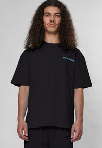 Schwarzes Baumwoll-T-Shirt mit lockerer Passform, kurzen Ärmeln und türkisfarbenem Text "9N1M SENSE." auf der linken Brust.