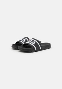 Svarta halkfria sandaler i gummi, med en bred rem som har vit och röd branding, samt en texturerad fotbädd för bättre grepp.