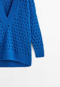 Niebieski dziany sweter o luźnym kroju, z dekoltem w serek i otwartym wzorem ściegu. Żebrowane mankiety i dół dodają tekstury.
