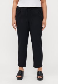 Pantaloni neri leggeri con vita elasticizzata e cordino, caratterizzati da un design a gamba affusolata e una texture liscia e morbida.