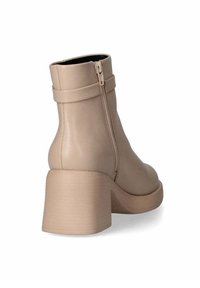 Stivali alla caviglia beige in pelle con una cerniera laterale, punta rotonda e tacco spesso. Texture liscia con dettagli minimi e design impilato.